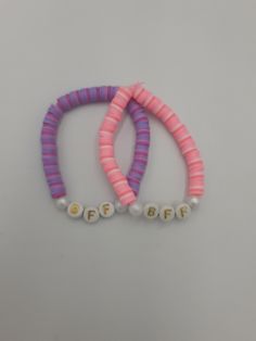 two pink and purple bracelets with pearls on the end of each beaded strand