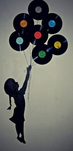 a child holding onto some vinyl records and flying them in the air with their hands