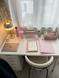 a white desk topped with a laptop computer next to a lamp and other office supplies