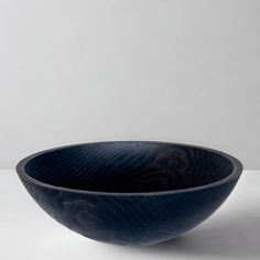 a blue bowl sitting on top of a white table next to a black object in the background