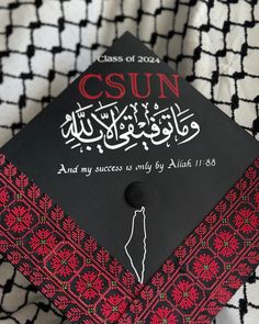 a black and red graduation cap sitting on top of a white and black patterned blanket