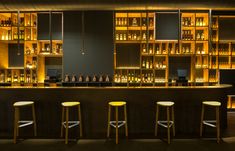 the bar has three stools in front of it and several bottles on the shelves