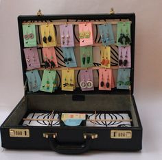 an open suitcase filled with lots of earrings and earring hooks hanging from it's sides