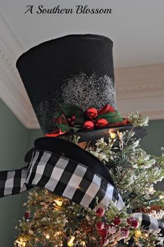 a black and white top hat with red berries on it is sitting on a christmas tree