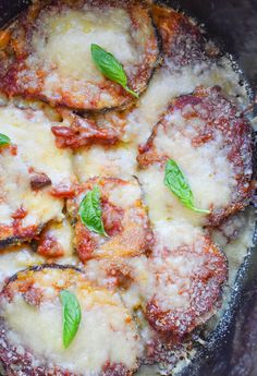 some food that is sitting on top of a pan with sauce and green leafy leaves