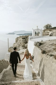 a bride and groom are walking down the stairs to their wedding ceremony in front of the ocean