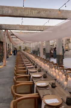 a long table with candles and plates on it is set up for an outdoor event