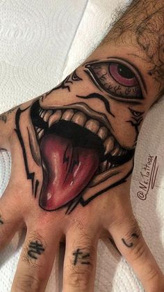 a person's hand with tattoos on it and an evil face painted on the palm