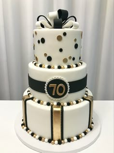 a three tiered white cake with black and gold decorations