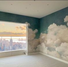 an empty room with a large window overlooking the city and clouds painted on the wall