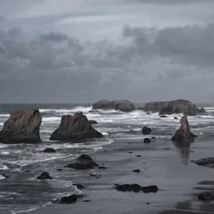 some very big rocks by the ocean on a gloomy day with no one in it