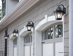 three lights on the side of a house next to two doors and windows with shutters