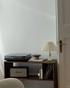 a record player sitting on top of a wooden shelf next to a lamp and chair