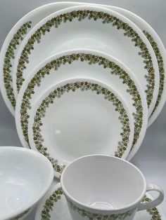 a stack of white dishes with green designs on them