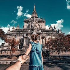 a man holding the hand of a woman in front of a castle