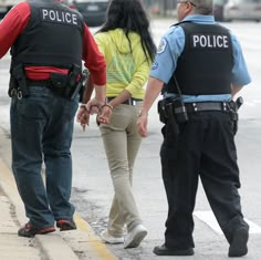 two police officers standing next to a woman on the side of the road with her hand in her pocket