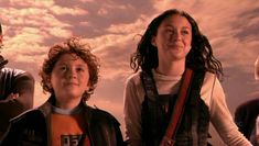 two children standing next to each other with the sky in the background and clouds behind them