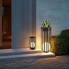 two planters with plants in them sitting on the side of a door way at night