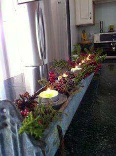 a kitchen counter with candles on it and evergreens in the middle, surrounded by pine cones