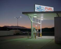 a gas station at night with the sun setting