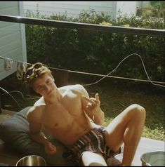 a shirtless young man sitting on a patio