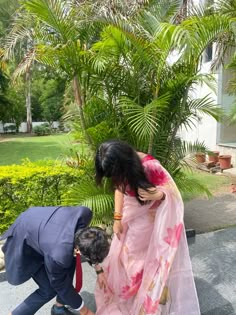 two people are bending over to pick up something from the ground in front of them