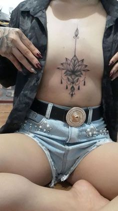 a woman sitting on the floor with her stomach covered in tattoos