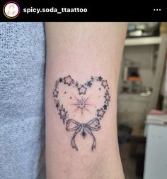 a heart shaped tattoo with stars and bows on the side of the arm is shown