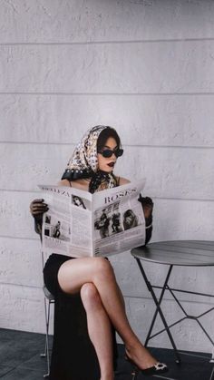 a woman sitting on a chair reading a newspaper