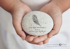 a person holding a rock with a feather on it in their hands, which reads rachel howard