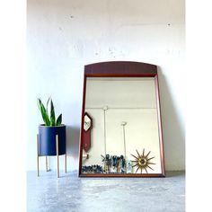 a mirror sitting on top of a table next to a potted plant and clock