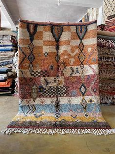 an area rug with many different colors and patterns on the floor in front of stacks of blankets