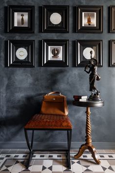 a small table with a purse on it in front of some framed pictures and a statue