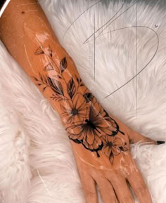 a woman's arm with flowers on it and a black ink design in the middle