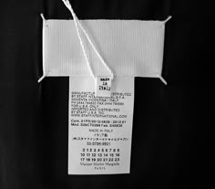 a white tag hanging from the side of a black jacket with strings attached to it