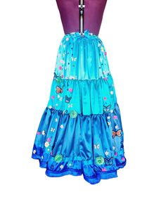 a blue dress with butterflies and flowers on the skirt is hanging from a mannequin