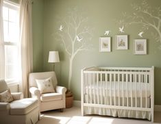 a baby's room with a white crib and tree decals on the wall