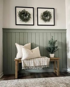 two framed wreaths on the wall above a bench with white pillows and throw pillows