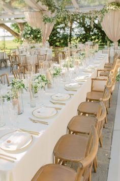 a long table is set with white linens and gold chargers