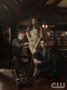 two men and a woman posing in front of a bookshelf