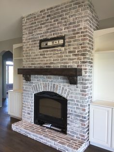 an empty living room with a brick fireplace and tv on top of the mantel