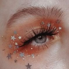 a woman's eye with stars painted on her lashes and eyelashes, as well as the