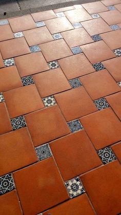 an orange and black cat sitting on top of a red tiled floor next to a white fire hydrant