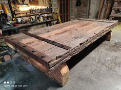 an old wooden table in a workshop with tools on the wall and shelves behind it