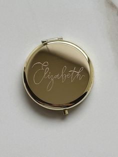 a compact mirror with the word elizabeth written in cursive writing on it's side