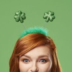 a woman with red hair and two green shamrocks on her head