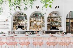 the bar is decorated with greenery and pink chairs, which are lined up against the wall