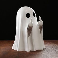 a white ghost figurine with two hands up in front of it's face