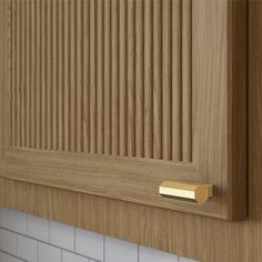 a close up of a wooden cabinet door with white tiles on the wall behind it