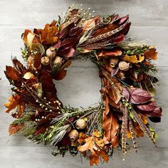 a wreath with autumn leaves and berries hanging on a wall